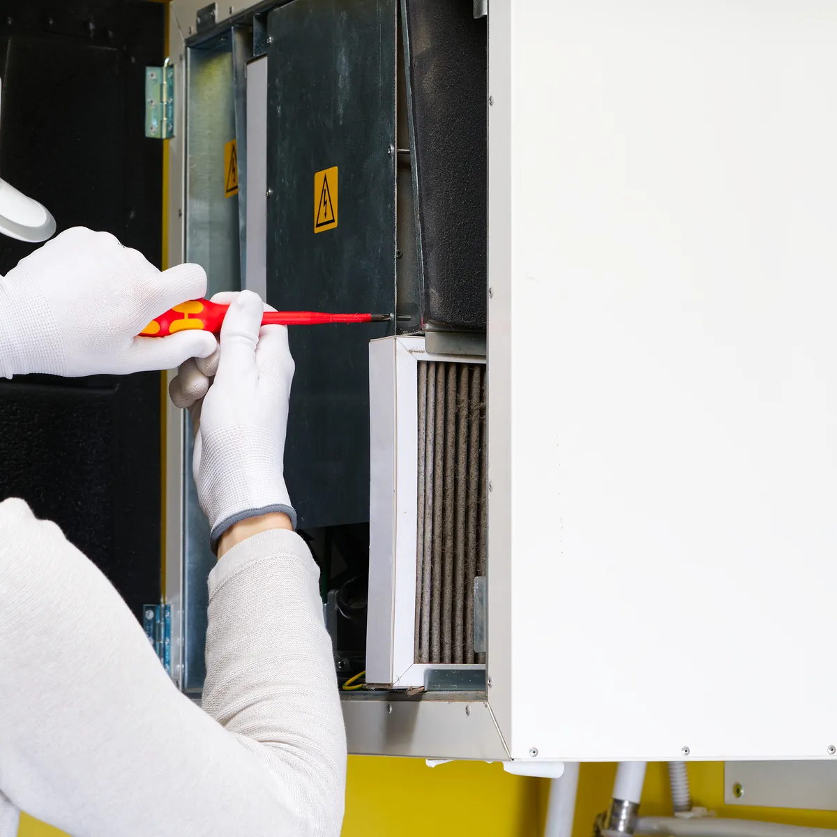Techniker mit Helm arbeitet an einem geöffneten Gerät.